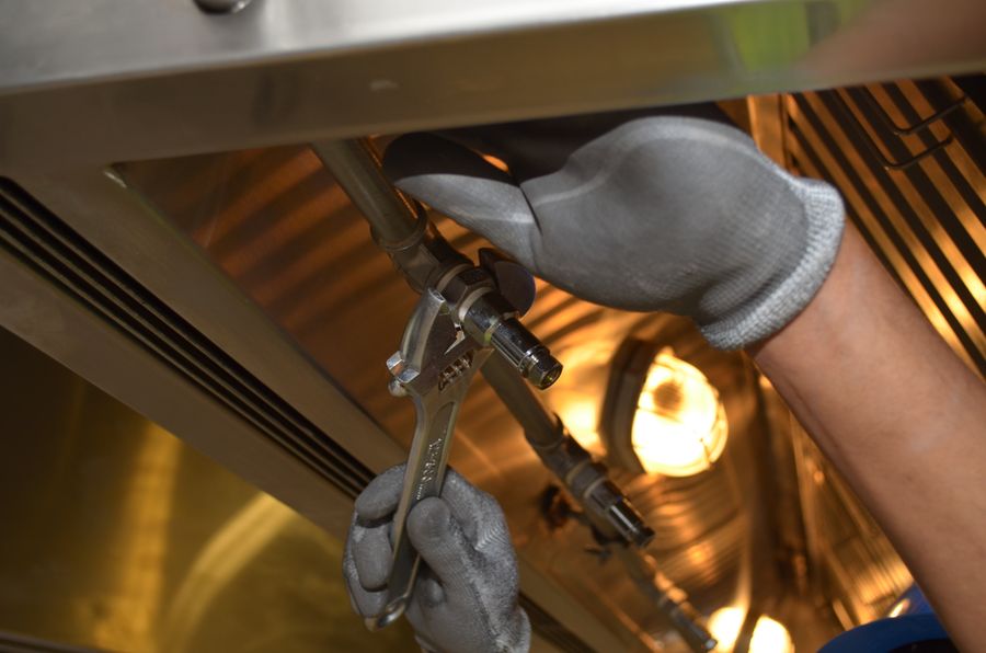 Gloved hands tightening a pipe fitting during a well pump replacement