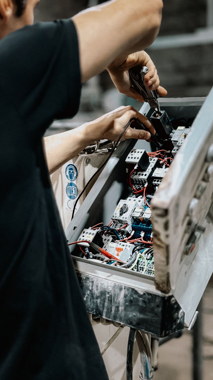 Technician repairing wiring inside an electrical control box