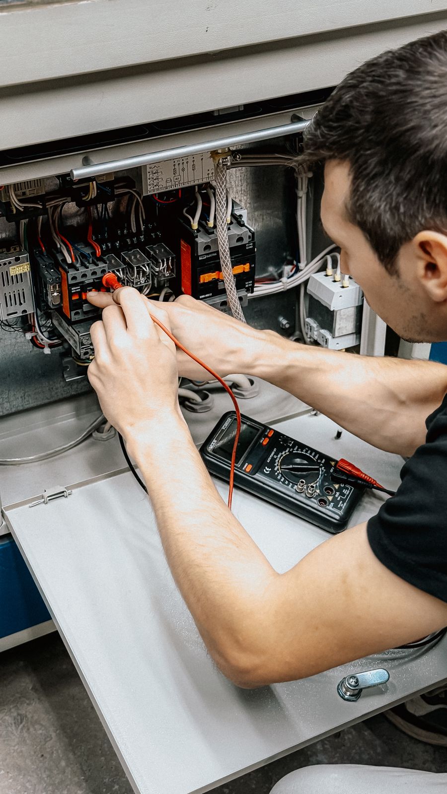 Technician testing well pump electrical components with a multimeter